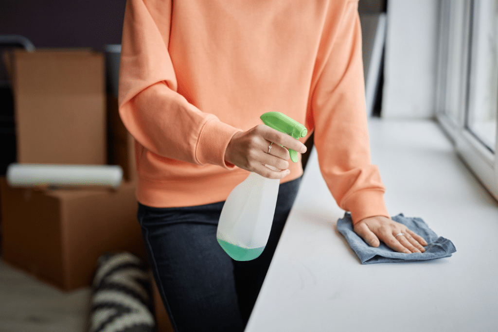 Person wiping a countertop with cloth and spray in a modern home keeping surfaces clean and fresh.