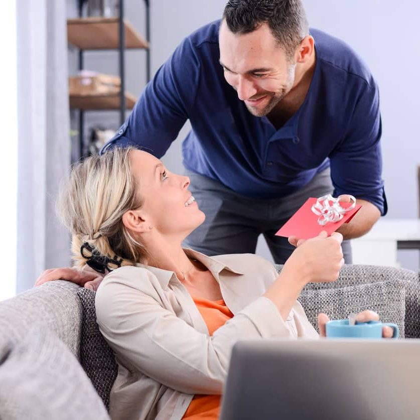 handsome man offering surprise present invitation in envelope gift to his young woman valentine girlfriend